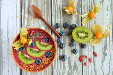 Acai smoothie bowl with blueberry, kiwi, physalis, goji berry, chia seeds and bee pollen. Top view