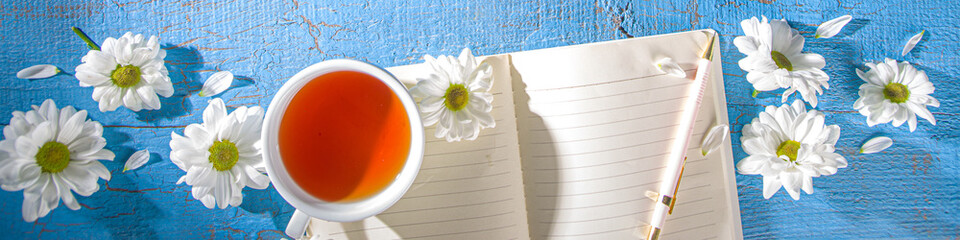 Chamomile flowers, notebook and tea background