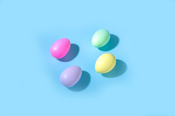 Creative simple pattern made of colorful bright Easter eggs with hard light on blue background. Minimal Easter holiday concept