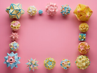 Fototapeta na wymiar Set of multicolor handmade modular origami balls or Kusudama Isolated on pink background. Visual art, geometry, art of paper folding, paper crafts. Top view, close up, selective focus, copy space.