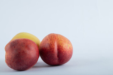 Ripe nectarines lie near a Cup of tea on a white background.