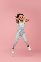 Fototapeta na wymiar Jumping. Happy longhair brunette little girl isolated on pink studio background with copyspace for ad. Looks happy, cheerful, sincere. Childhood, education, human emotions, facial expression concept.