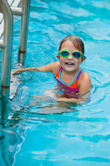 Little girl taking a break during swimming swim lessons at the local outdoor pool