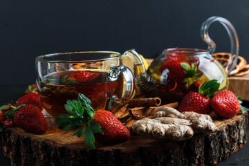 Fruit red tea with wild berries in a glass cup, on a wooden table, on a dark background