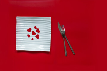 read hearts on a white plate as a symbol of love. romantic dinner. red background