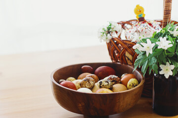 Modern eggs, Easter bread in wicker basket, bunny and blooming spring flowers on rustic table