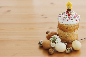Delicious homemade Easter bread, stylish easter eggs, spring flowers on rustic table. Happy Easter