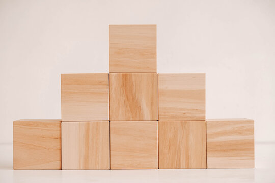 Pyramid of wooden blocks from natural wood on a white background. Copy, empty space for text