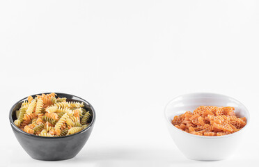 Two bowls of raw pasta on white background