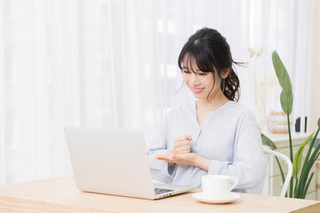 Fototapeta premium 部屋でノートパソコンを使いながら納得のジェスチャーをする若い女性