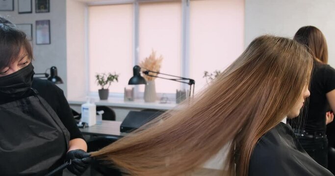 Professional hairdresser combs the hair of a girl in a beauty salon