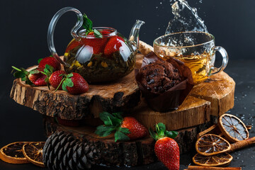 Fototapeta na wymiar Fruit red tea with berries in glass teapot on black background