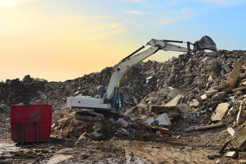 Recycling concrete and construction waste from demolition. Excavator at landfill of the disposal. Reuse of building rubble. Backhoe dig gravel at mining quarry on sunset background. Concrete debris