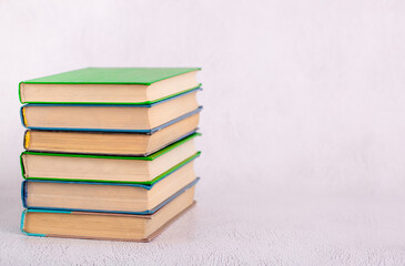 Books stacked on a light table. Learning and reading hobby. A set of books for a student or schoolboy. School and university, gaining knowledge. Light background with copy space.