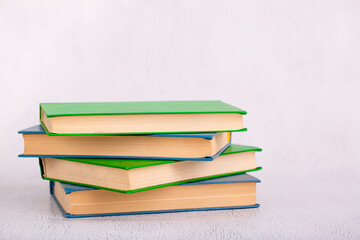 Books stacked on a light table. Learning and reading hobby. A set of books for a student or schoolboy. School and university, gaining knowledge. Light background with copy space.