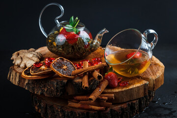 Fototapeta na wymiar Fruit red tea with wild berries in a glass cup, on a wooden table, on a dark background