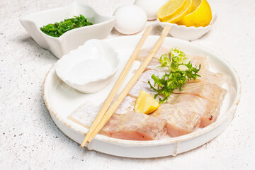 Pieces of raw hake, chukka salad, lemon wedge, fresh herbs, eggs as food preparation concept
