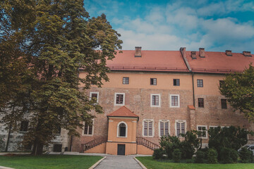 View of Cathedral museum, green lawns, sidewalk, trees and bushes on Wawel Hill known as the Wawel Cathedral in Krakow Royal Castle on sunny autumn day. One of most popular landmarks in Poland