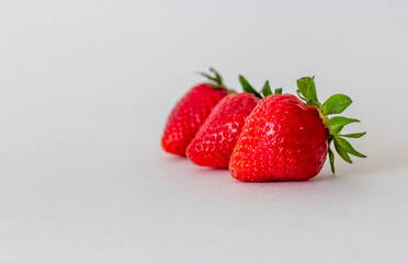 Three strawberries lie on a blue isolated background. There is a place to write