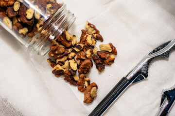 walnut kernels scattered from the jar lie on a napkin next to the nutcracker