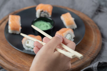 Salmon rolls with cream cheese in a black plate with wasabi sauce