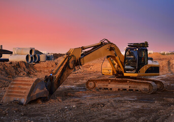 Excavator on earthworks at construction site on sunset backround. Excavators on foundation work....