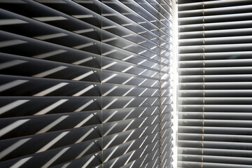 Bright sunshine seen through closed venetian blinds on two windows