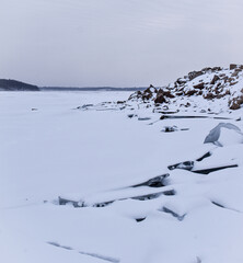 Fototapeta premium Ice perched on rock from a frozen snowy lake