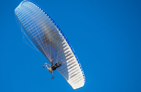 Person flying with a moto paraplane in the blue sky
