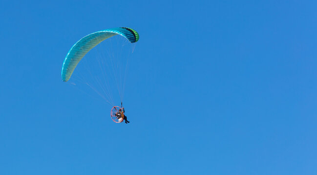 Person flying with a moto paraplane in the blue sky