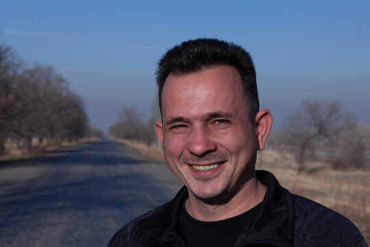 A brutal young man, dark-haired 36 years old in a sports jacket, against the background of the snow-white mountains of Tien Shan