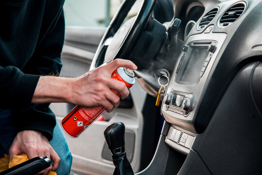 Detalle de una mano masculina con un spray pulidor para limpiar el salpicadero de un coche. Concepto de trabajador de lavado de coches. Ambientador