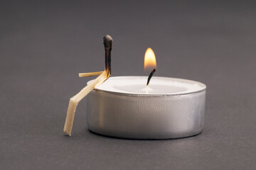 Matchstick character sitting on a lit tea candle. Unrequited love concept.