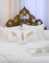 cama e cabeceira de cama com lençóis clássicos e tabuleiro  com loiça branca 