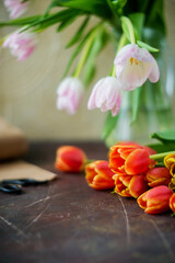 red spring tulips on a blue textured background, next to twine rope and scissors, preparing bouquets for the holiday