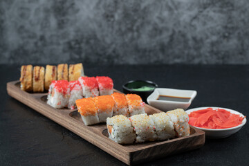 Sushi set on a wooden platter with soy sauce, ginger and wasabi