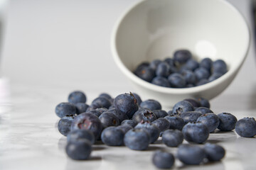 A group of fresh blueberries on a white and black marble table. 