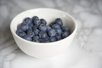 A group of fresh blueberries on a white and black marble table. 