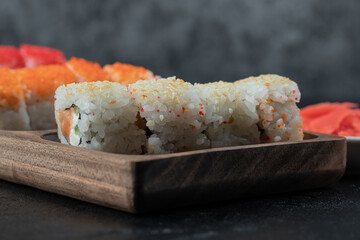 Sushi set isolated on a wooden board on black background