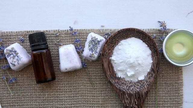 Flat lay view of small cube shape bathroom bath fizzies on wood tray, surrounded by ingredients. Making homemade small bath fizzy.