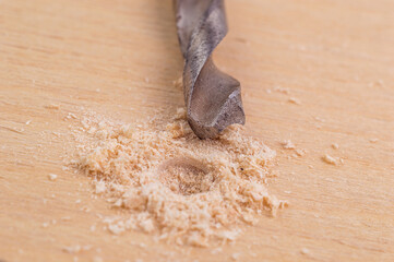 the drill has made a hole in the wood. on a white background. hand tool concept. selective focus.