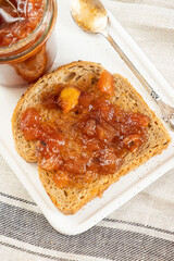 Homemade apple jam marmalade with cloves and cinnamon from organic apples  in glass jar and  wholemeal bread near vintage teaspoon. Homemade autumn jam preserves. Apple jam sandwich  toast breakfast 