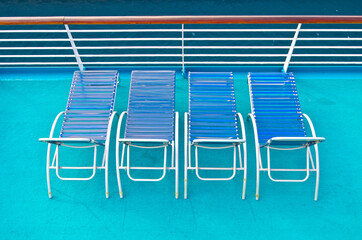 Outdoor pool deck with sun loungers and deck chairs on modern cruiseship or cruise ship liner