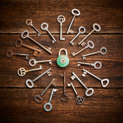 Vintage rusty padlock surrounded by group of old keys on a weathered wooden background. Internet security and data protection concept, blockchain and cybersecurity