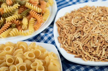 Variety of dry pasta on white plates