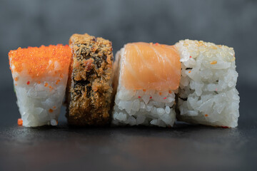 Mini sushi rolls with mixed ingredients on black background