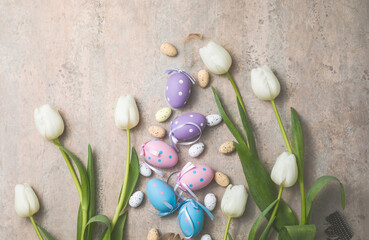 Easter composition with colorful Easter eggs and spring flowers  tulips on concrete background. Easter card  copy space