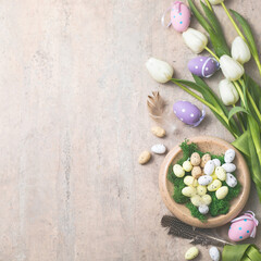 Obraz na płótnie Canvas Easter composition with colorful Easter eggs and spring flowers tulips on concrete background. Easter card copy space