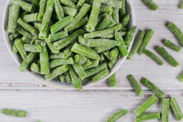 Top view composition with organic frozen vegetables on a white wooden background