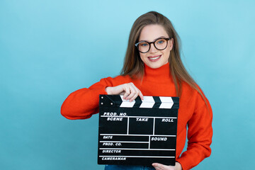 Pretty woman with long hair wearing a casual sweater and glasses over blue background holding...
